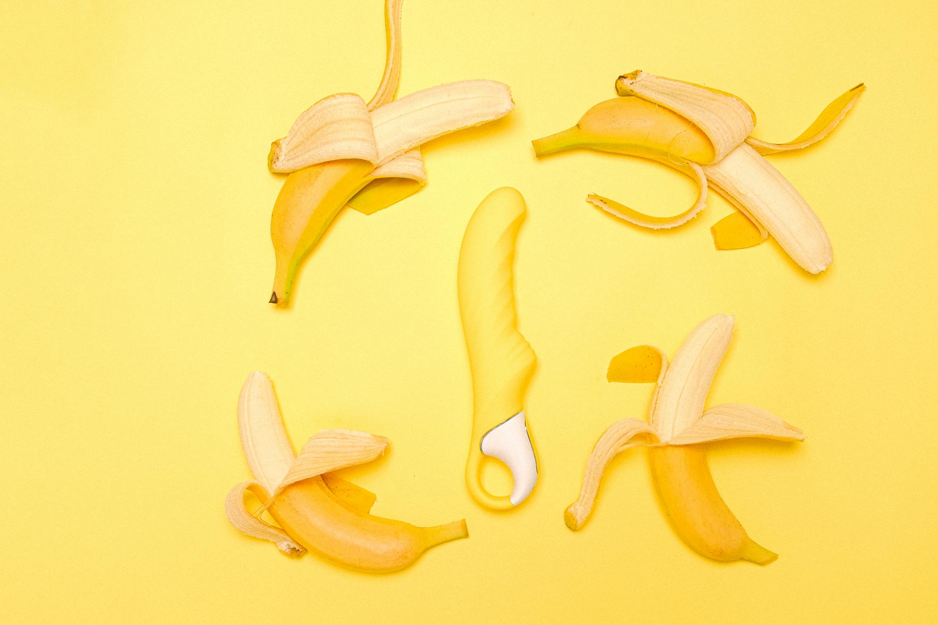 Yellow silicone lemon vibrator surrounded by fresh fruit on a bright yellow background