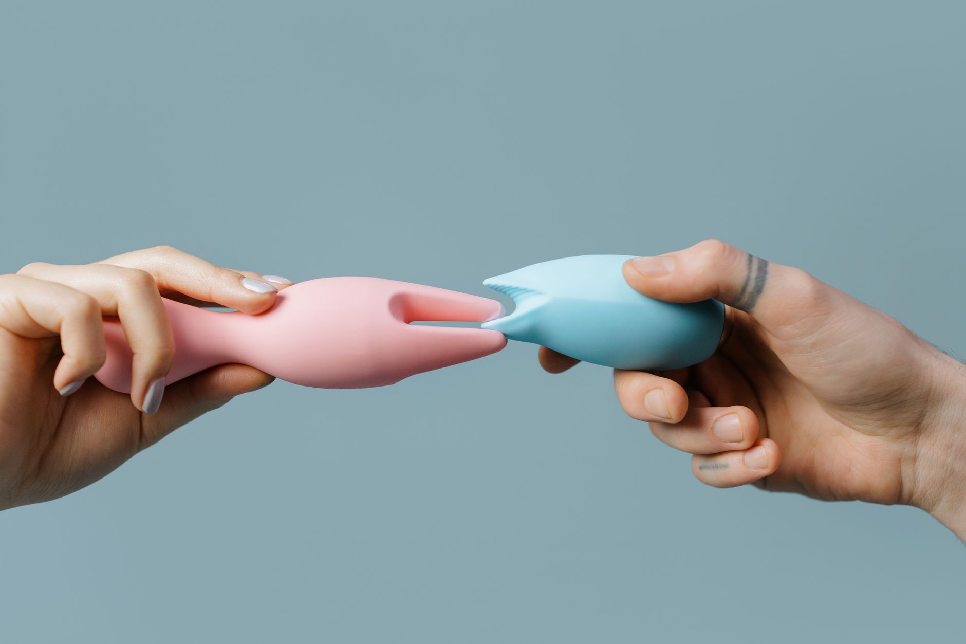 Person holding a blue and pink silicone vibrator with intention and care