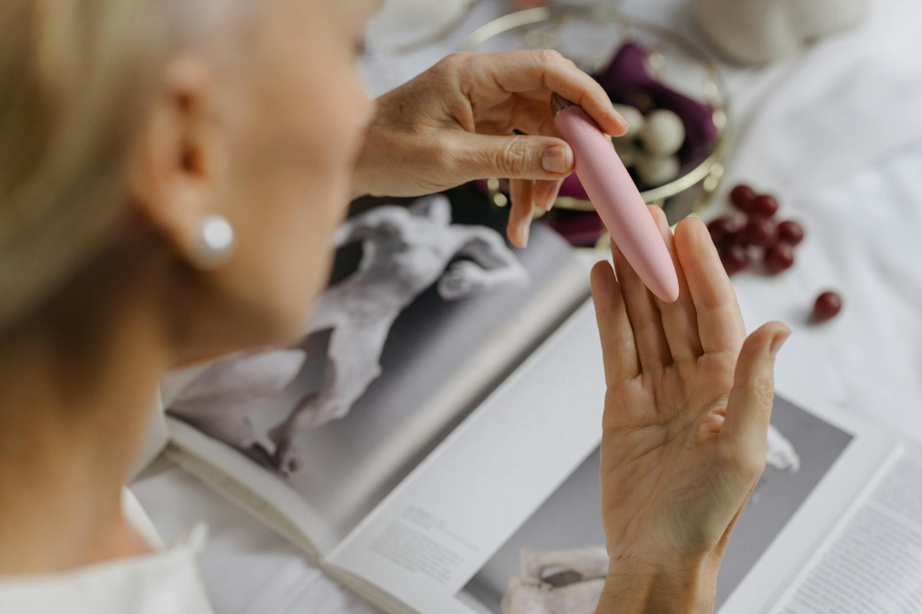 Woman holding blue and pink silicone vibrators in a thoughtful moment, representing reconnection with pleasure